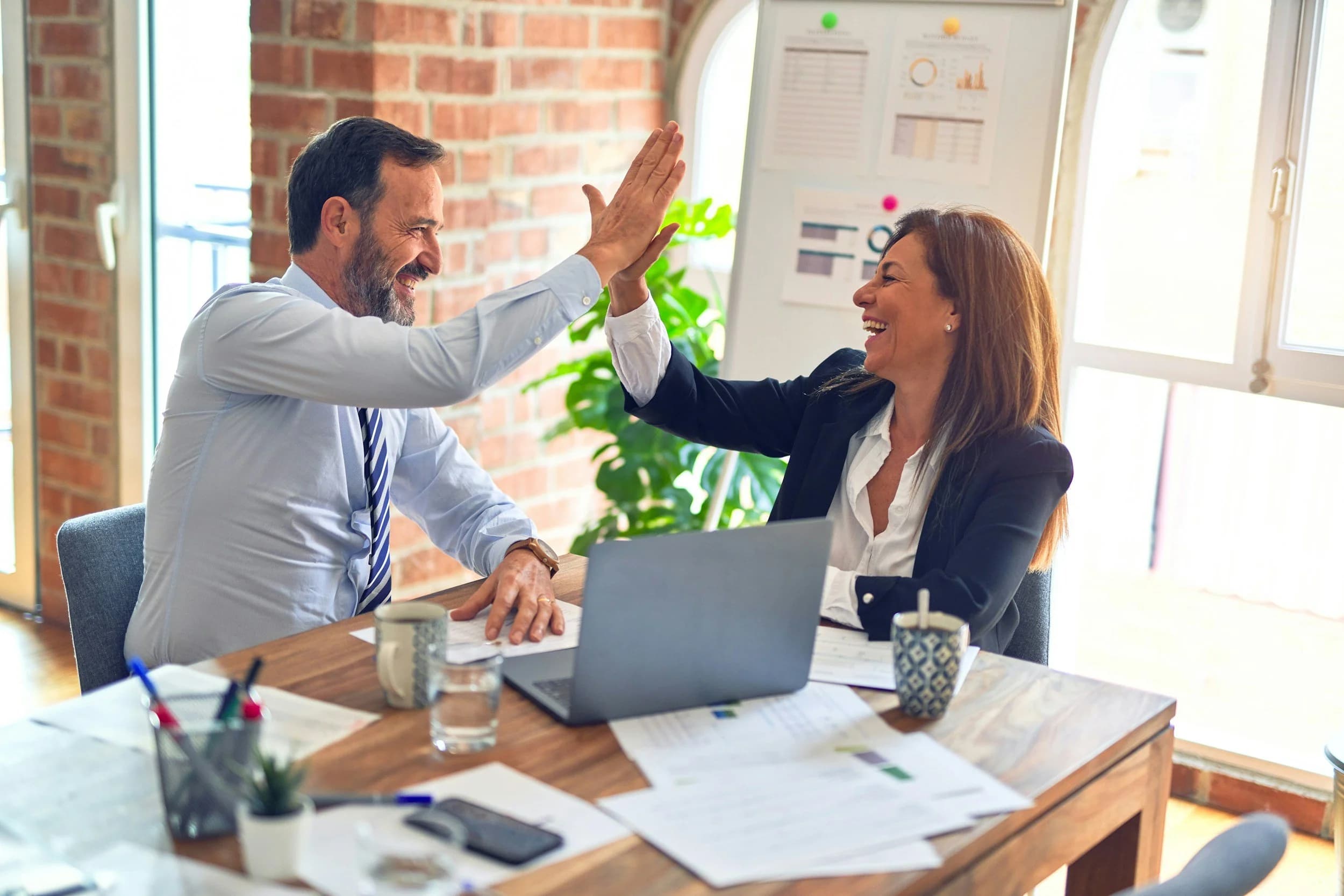 Two colleagues celebrating a closed account in a finance office